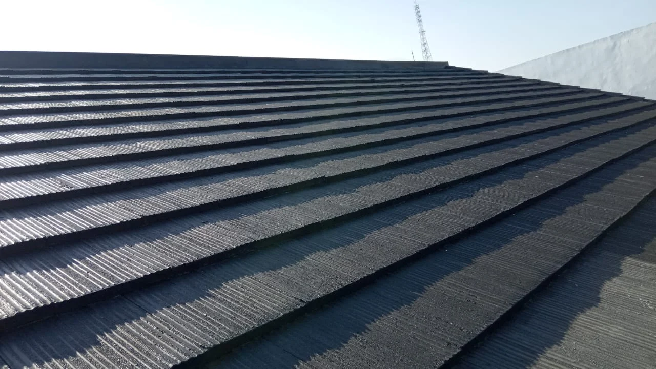 Barisan genteng beton warna gelap yang sudah terpasang rapi di bidang atap, terlihat dari dekat.